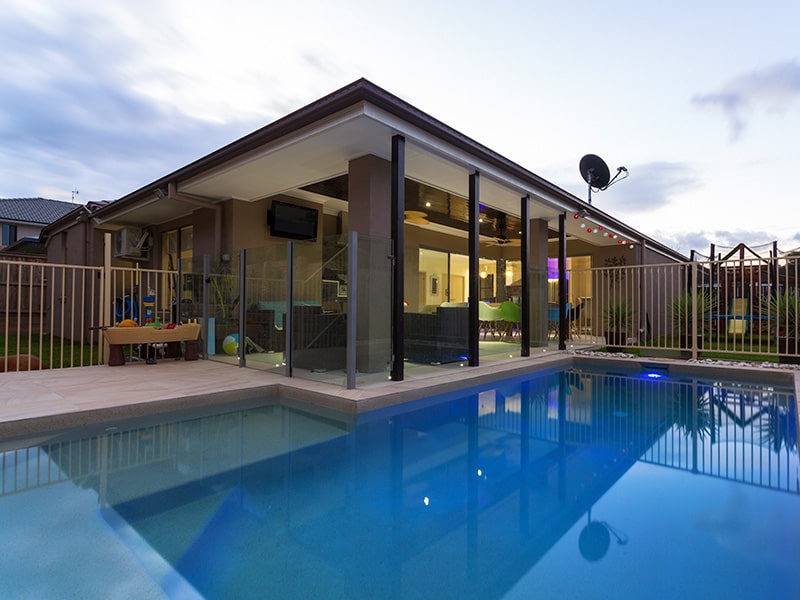 A modern pool within a residence, highlighted by a glass wall and surroundings